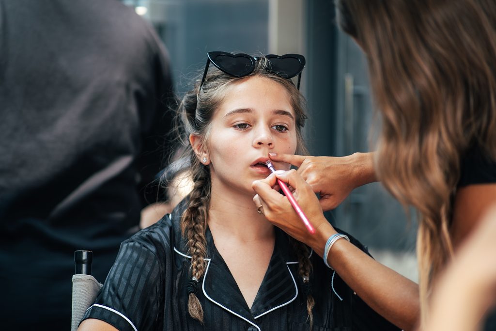 flower girl in black striped pyjamas has lipstick applied