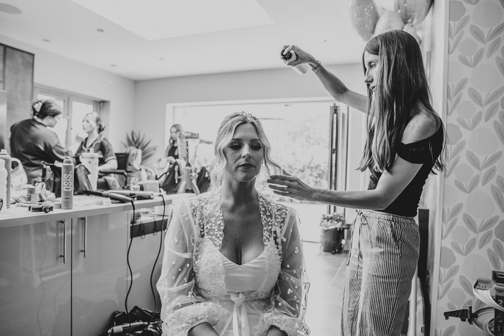 hairstylist finishes brides hair in kitchen as she preps at home