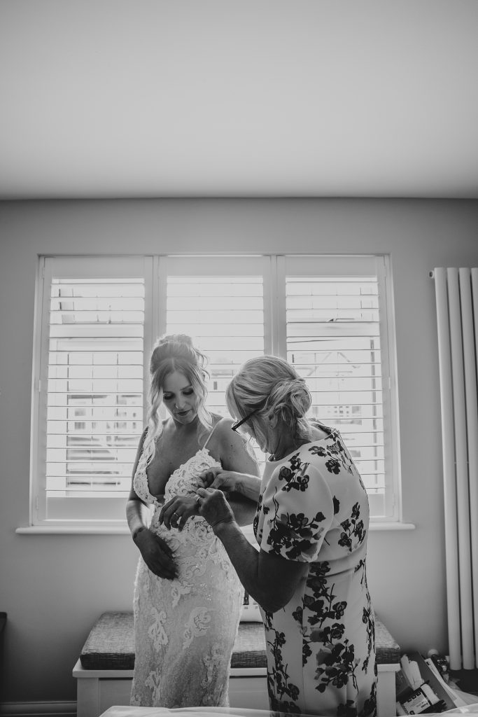 mum helps her daughter into wedding dress
