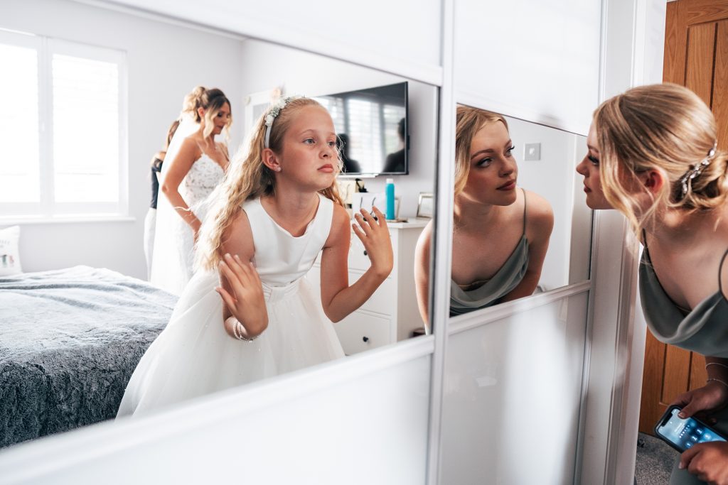 bridesmaid and flower girl check reflections in mirror