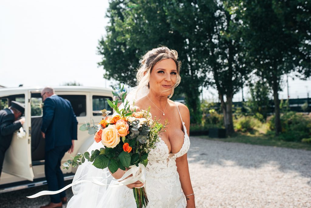 bride smiles as she steps out of car