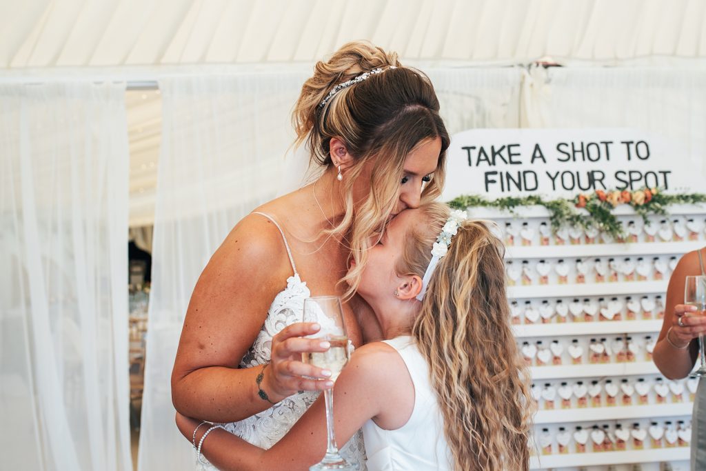 bride kisses daughter on head while drinking champagne