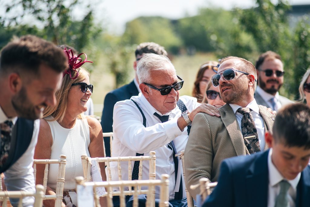 wedding guest rubs shoulders of person sitting in front of them
