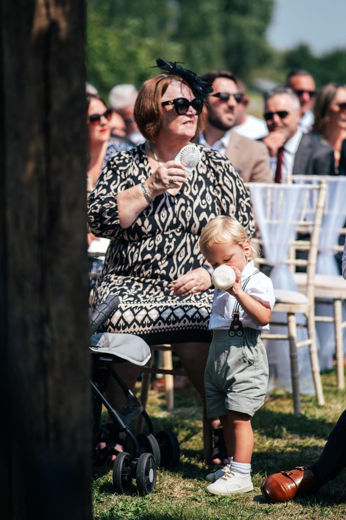 little boy drinks from a bottle of milk during wedding ceremony