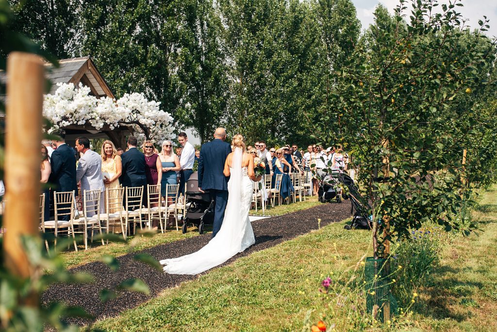 bride walks with father to outdoor ceremony