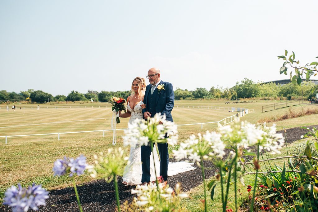 bride and father walk to outdoor wedding ceremony