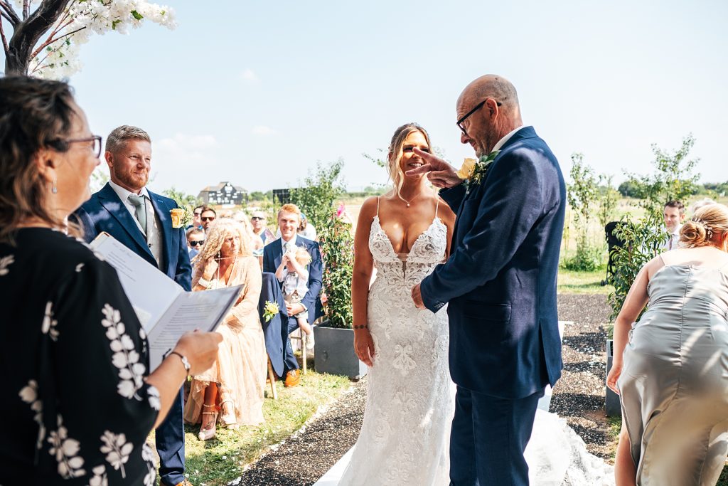 father of bride does chopping motion with his hand to groom after he walks daughter down aisle