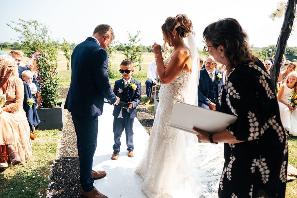 little boy in suit and sunglasses offers groom ring