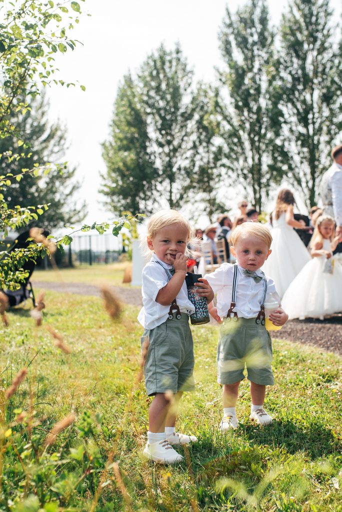 two toddler boys in braces and bow ties look at camera