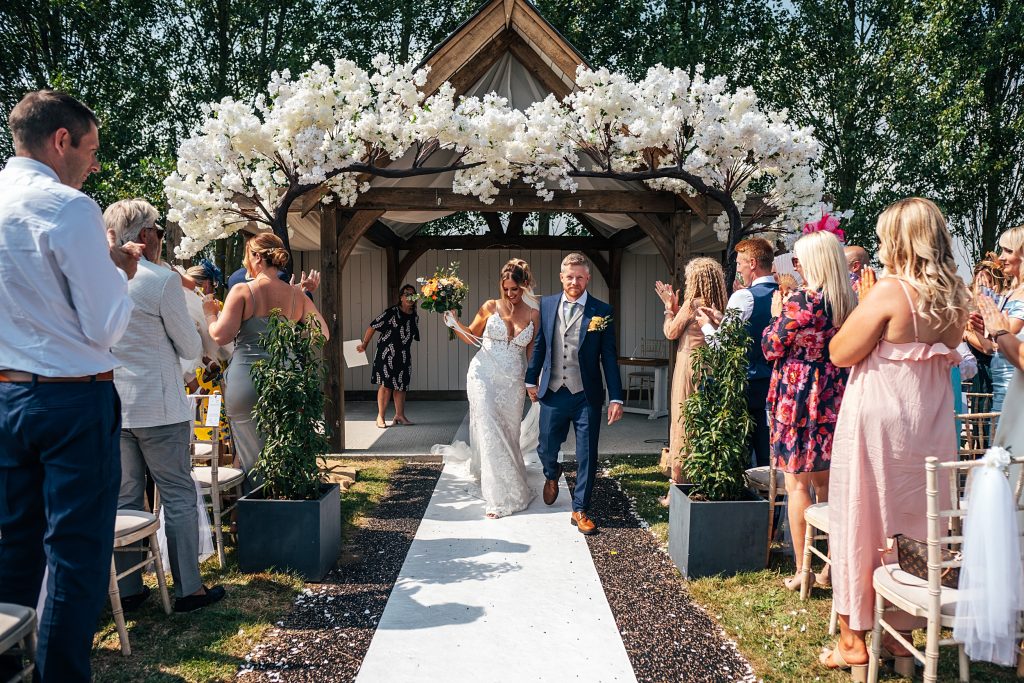 smiling bride and groom walk back up aisle after outdoor ceremony
