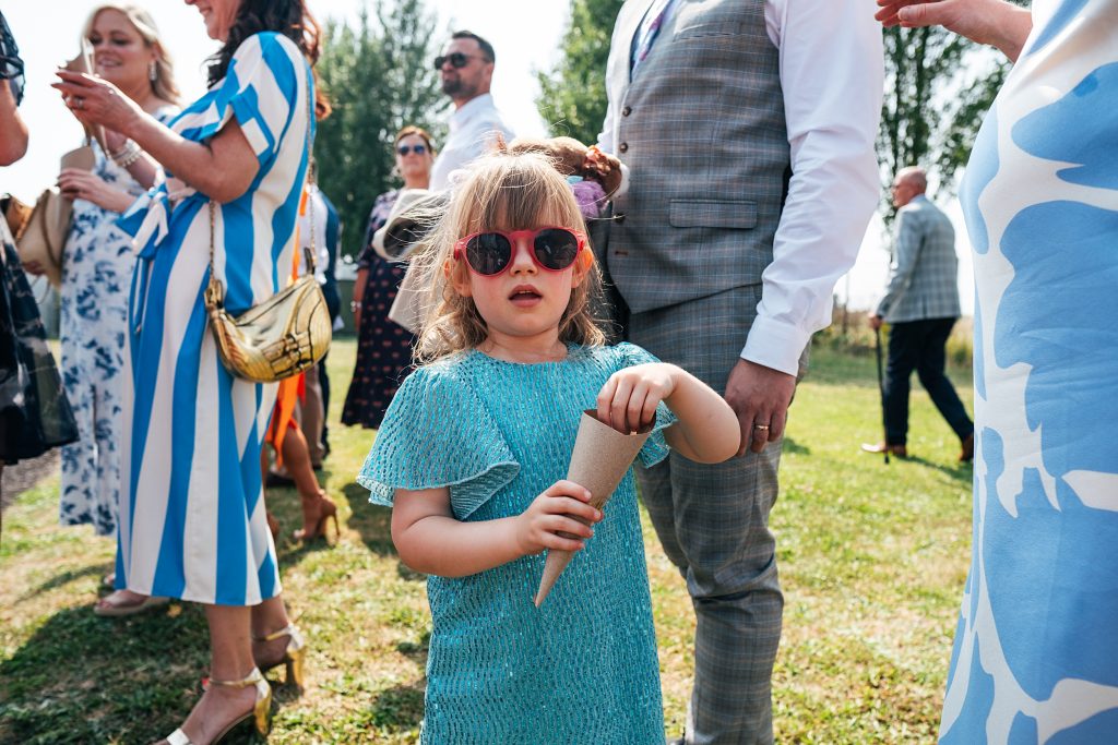 little girl in sunglasses holds confetti cone