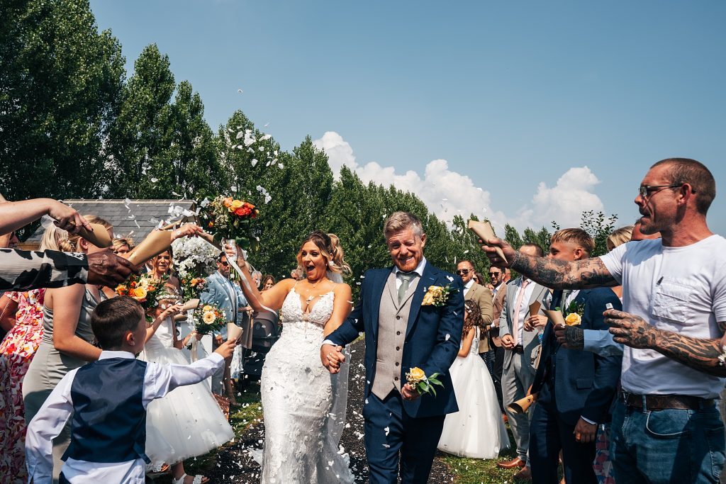 bride and groom look surprised as guest throw confetti