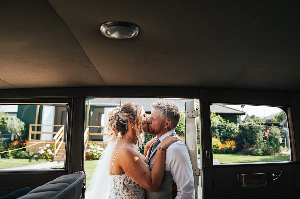 bride and groom kiss in car door