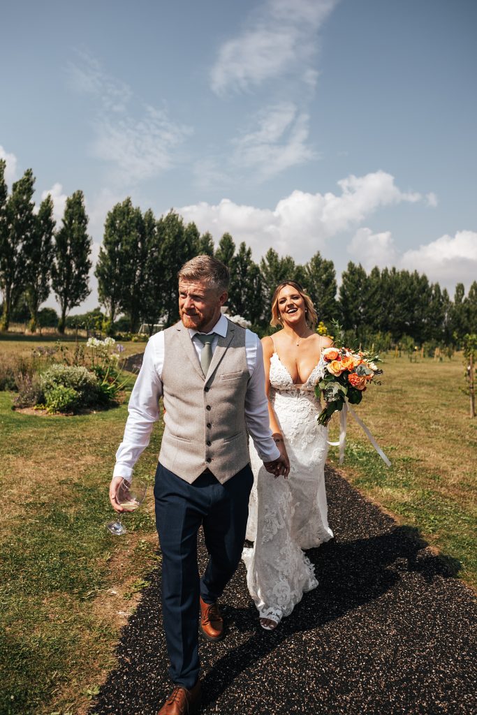 bride and groom laugh and walk towards camera