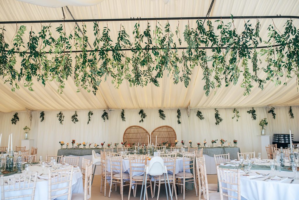 marquee with greenery on ceiling dressed for wedding
