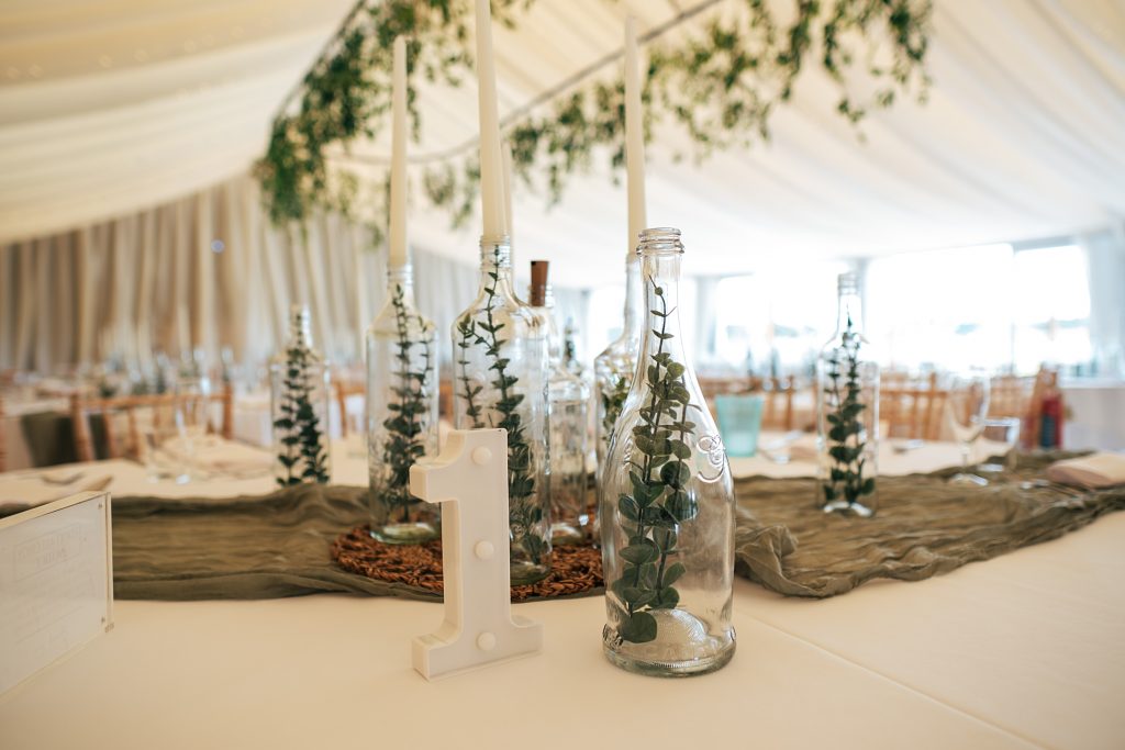 glass bottles with greenery on tables