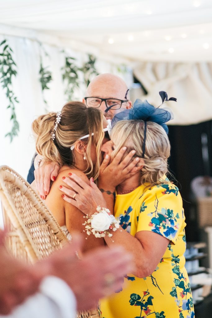 bride kisses her mum in marquee