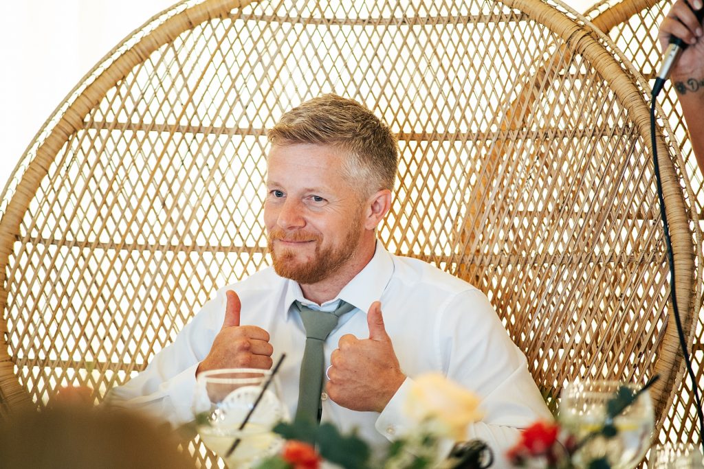 groom gives thumbs up during speech