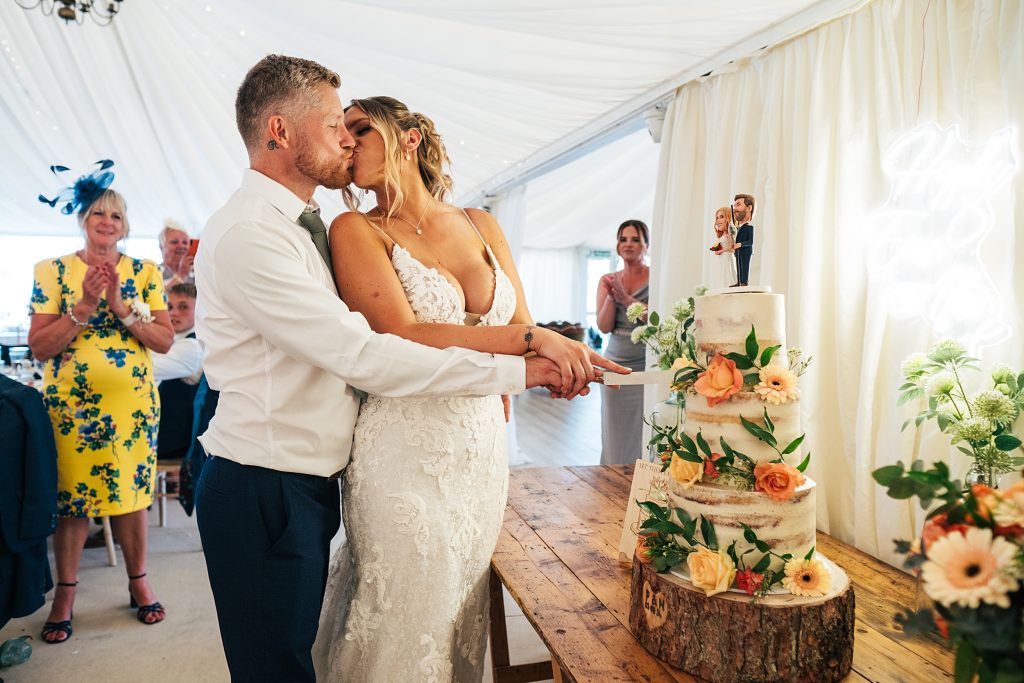 bride and groom kiss as they cut cake