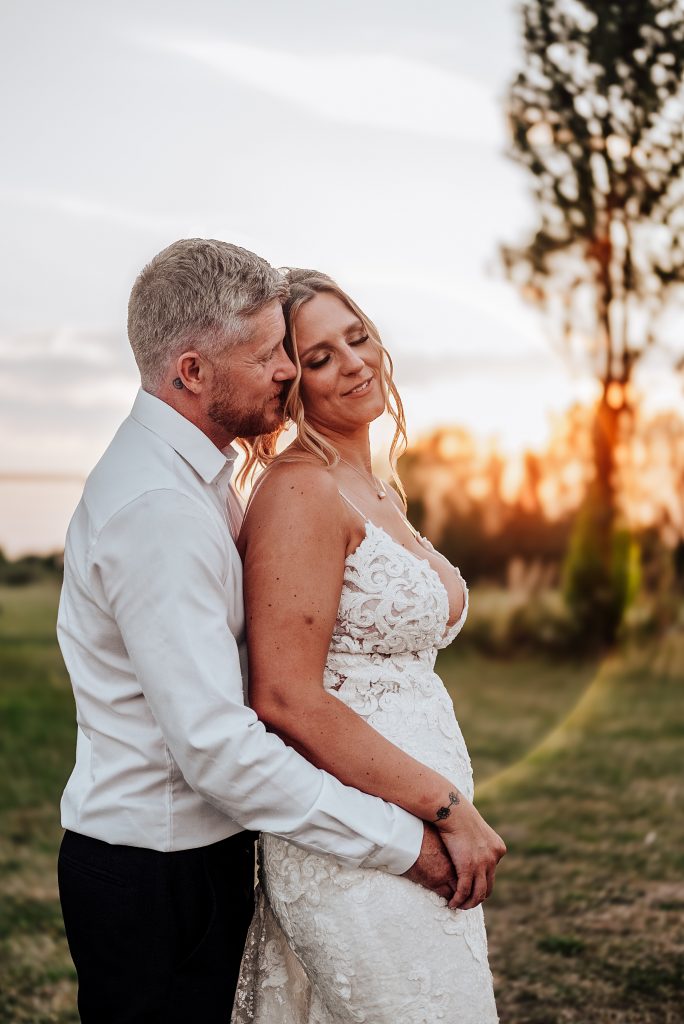 bride and groom in field at sunset