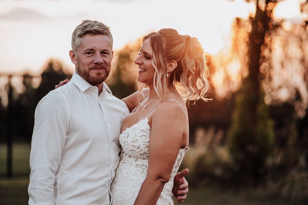 bride and groom in field at sunset